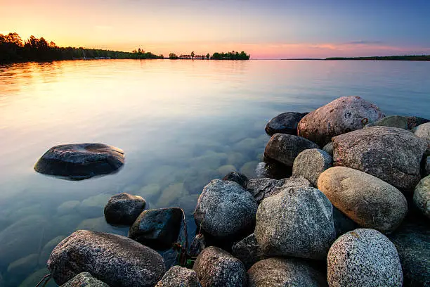 Photo of Large boulders on lake shore at sunset. Minnesota, USA