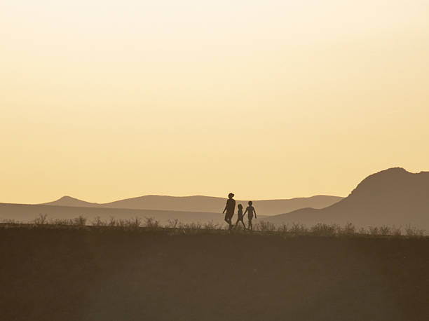 This family of hikers (silhouette) takes advantage of a desert trail along the top of a retaining dam within Las Cruces, New Mexico. The 700-acre site within city limits currently is being converted into a recreation area and wildlife preserve.
