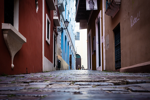 Old San Juan, Puerto Rico - March 29, 2015:   Cobblestone street seen photographed low angle from Old San Juan, Puerto Rico with colorful buildings and people walking in the distance.    Old San Juan is the oldest settlement within Puerto Rico and a popular tourist destination. 
