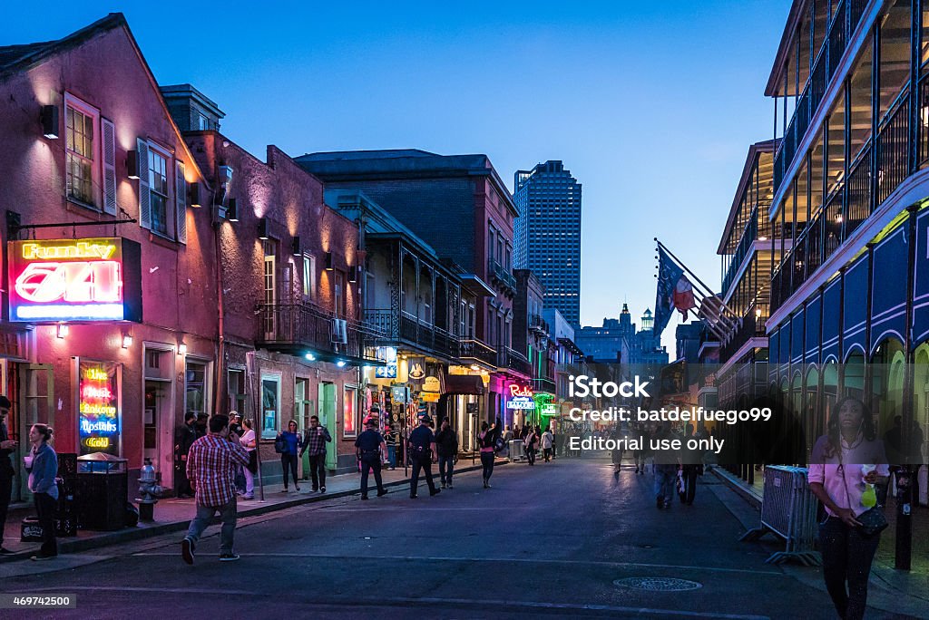 Perspective shot of Bourbon Street at dusk in New Orleans New Orleans, United States - November 2, 2014: People start partying on an early evening on Bourbon Street in downtown French Quarters. Street Stock Photo