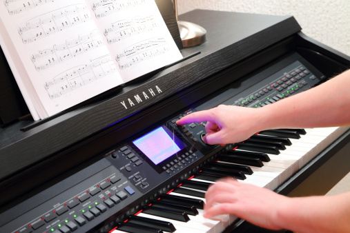 Ambronay, France - January 23, 2014: Interface of a CVP 601 piano from Yamaha sounds company. A unrecognizable pianist is being set sounds and other adjustment with his finger on a LCD and lots of buttons on his electronic keyboard.