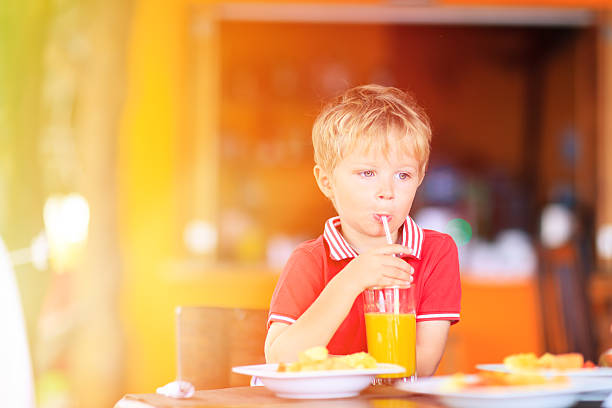 istock cute little boy drinking juice in cafe 469750122