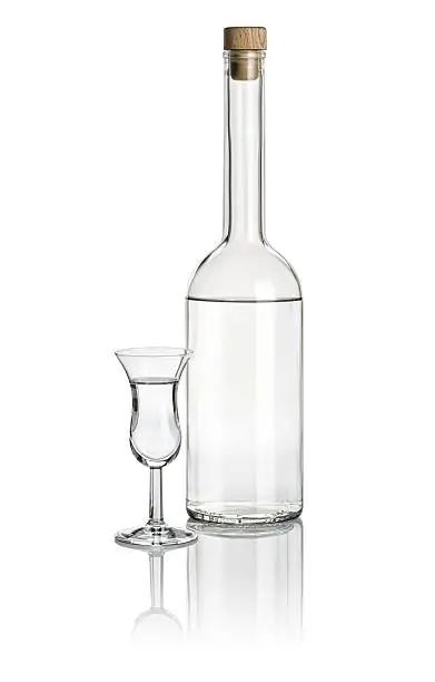 Liquor bottle and high stem glass filled with clear liquid