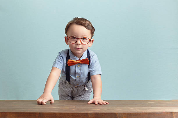 печальный маленький мальчик в оранжевый галстук и очки - bow looking at camera waist up indoors стоковые фото и изображения