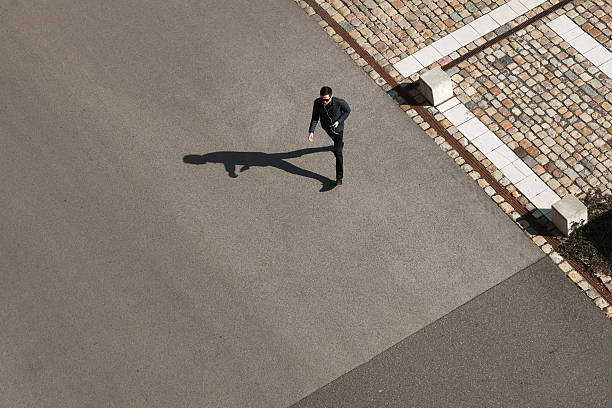 jovem homem a andar para a frente num dia soalheiro - shadow focus on shadow people men imagens e fotografias de stock
