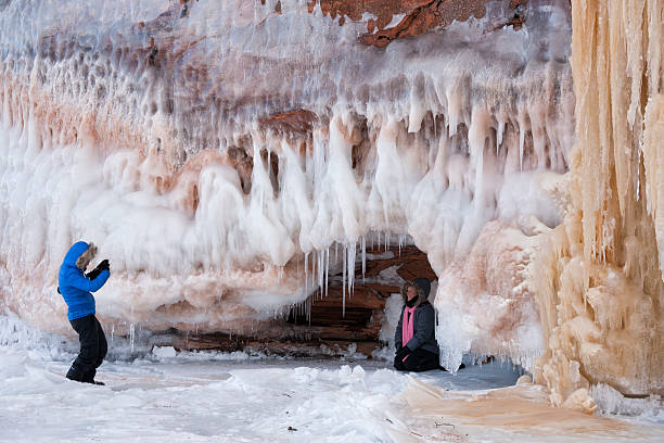 Two adult sisters have fun exploring and photographing each other at the ice caves at Apostle Island National Lakeshore, Cornucopia, Bayfield County, Wisconsin, USA