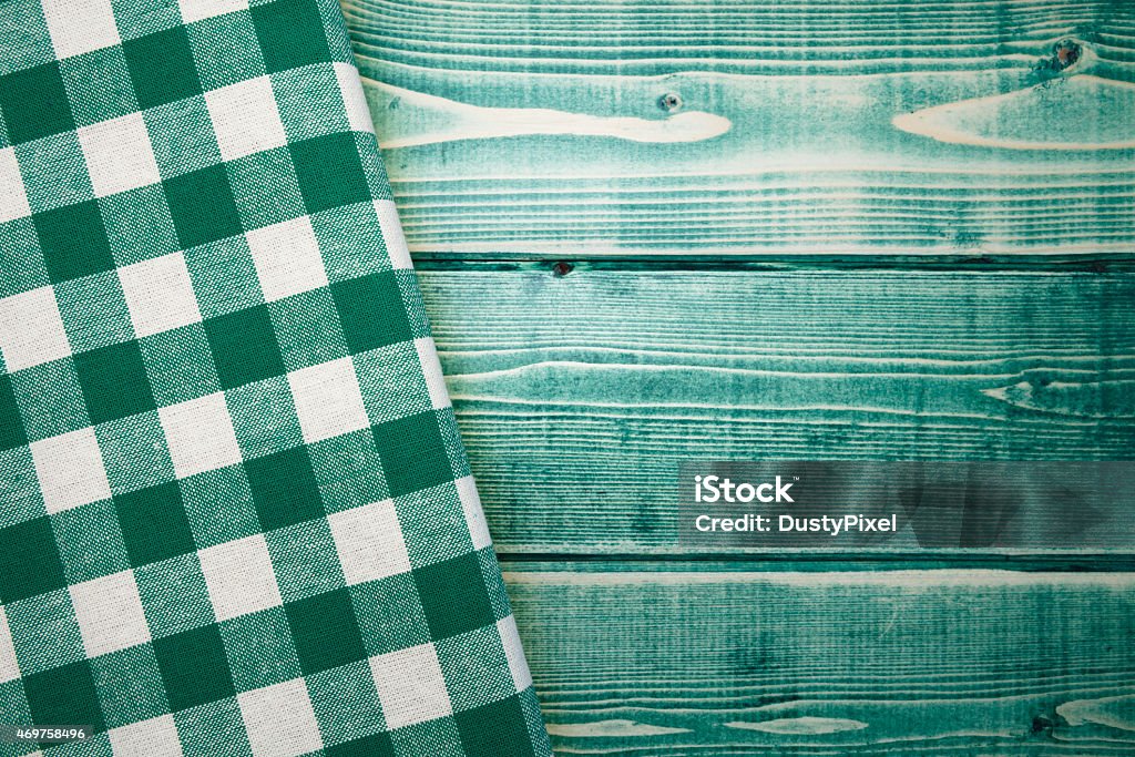 Green Checked Napkin on Green Wooden Picnic Table Up close view of a weathered rustic green picnic table. There is a green gingham print napkin draped across the left side of the table. 2015 Stock Photo