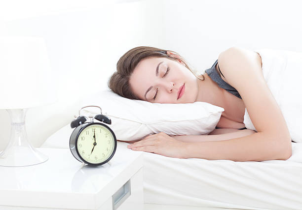 istock Young woman sleeping peacefully with alarm clock nearby 469762490