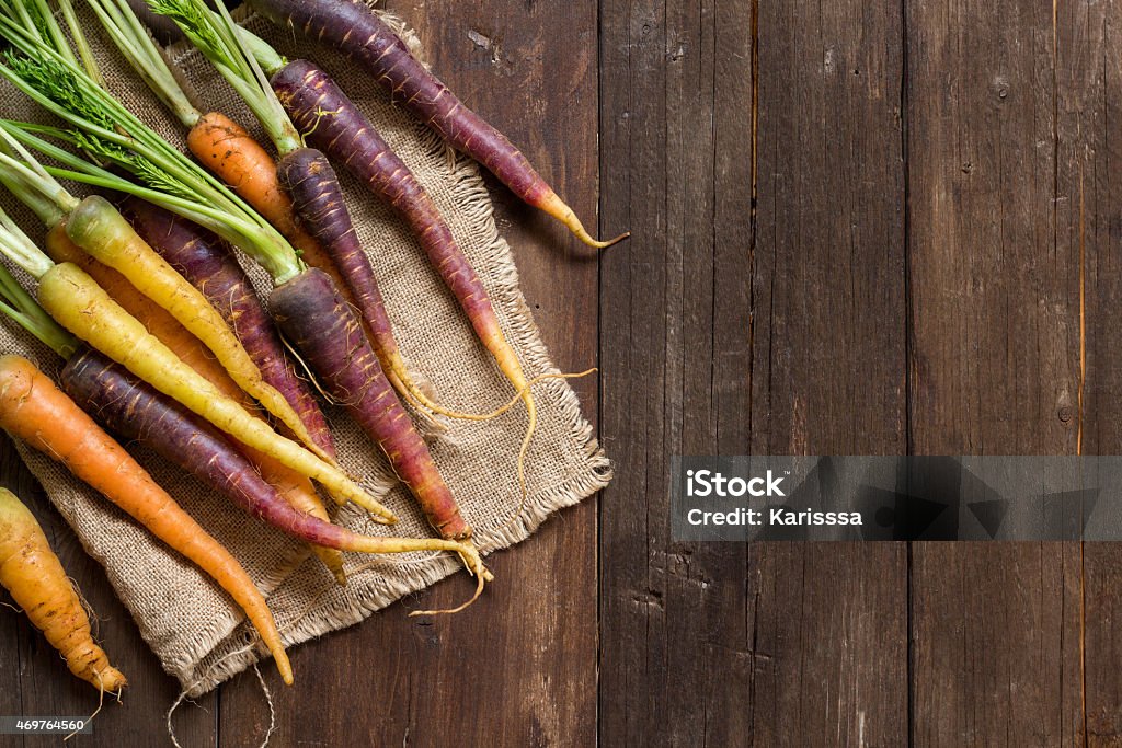 Fresh organic rainbow carrots placed on a wood table Fresh organic rainbow carrots on a wooden table 2015 Stock Photo