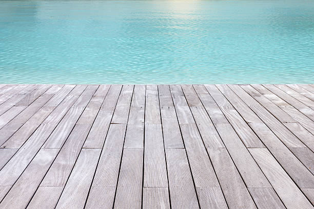 Wooden platform beside blue water. Wooden platform beside blue swimming pool background. boat deck stock pictures, royalty-free photos & images