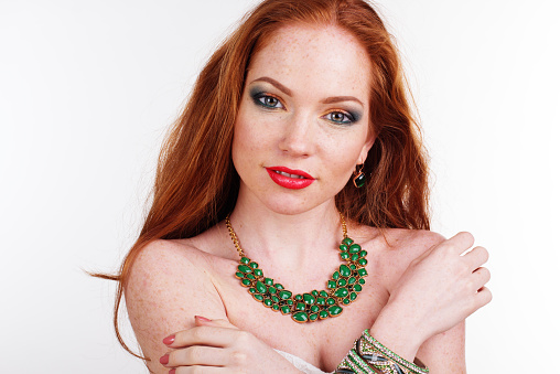 Portrait of beautiful redheaded girl with fashion colorful makeup is wearing green necklace