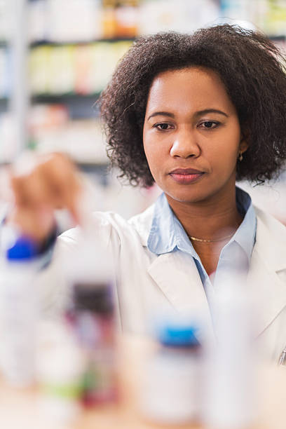 istock African American pharmacist in pharmacy taking pill bottles. 469769376