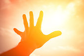 Hand reaching to sunshine sky.