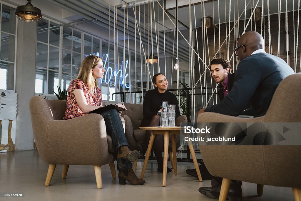 Diverse group of young people having a meeting in lobby Diverse group of young people having a meeting in lobby. Young business executives meeting in office sharing creative ideas. Panel Discussion Stock Photo