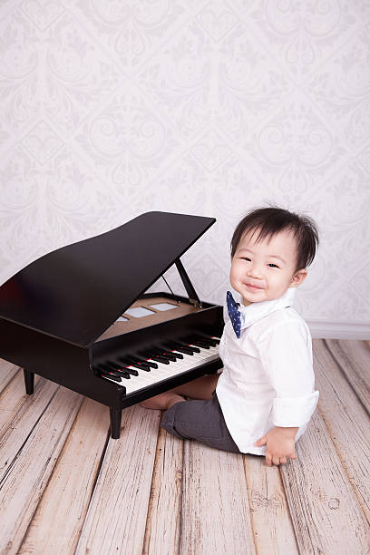 istock Cute boy sitting at toy piano smiling at camera 469774062