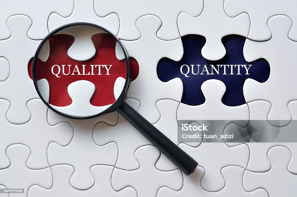Magnifying Glass On Missing Puzzle with "QUALITY/QUANTITY" Word, Antonym Concept Searching for Quality and Quantity concept Quality Control Stock Photo
