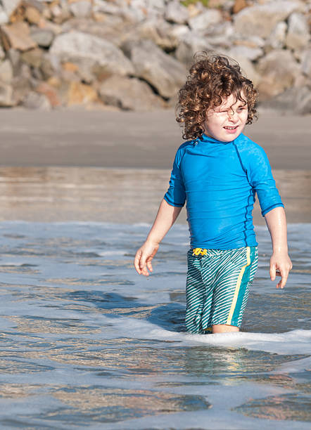 Caucasian boy  walking in the water in the beach.