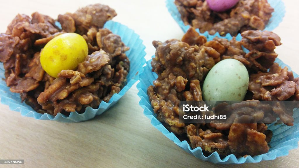 miniature easter egg nest Cornflakes covered in milk chocolate, topped with a miniature easter egg, in blue cupcake casings. Corn Flakes Stock Photo