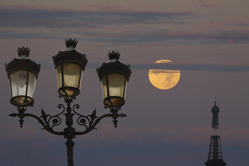 Photographic montage - the Eiffel Tower seen from the Place du Trocadéro with, in the foreground on the left, a street lamp and in the background, the full moon.