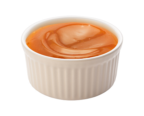 Creamy Caramel Syrup in a white ramekin. This sauce can be used for dipping, or as an ingredient. The image is a cut out, isolated on a white background, with a clipping path.