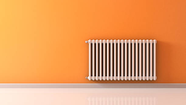 White wall-mounted radiator on an orange wall stock photo