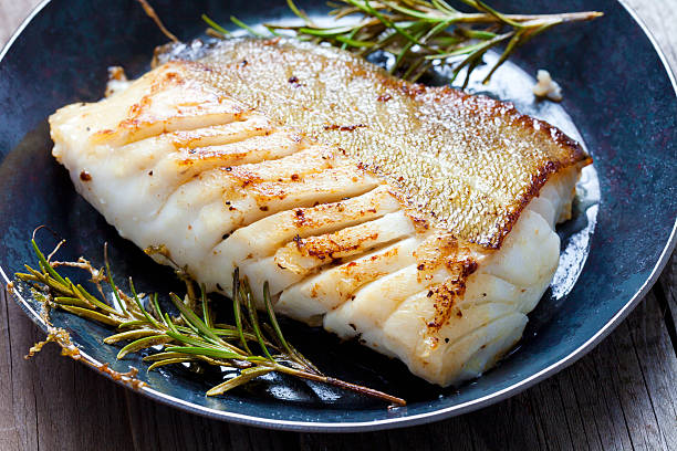 filetto di pesce fritto, atlantic cod con rosmarino in padella - prepared fish foto e immagini stock