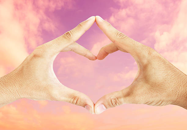 istock hand in heart form love on violet sky background 469784098