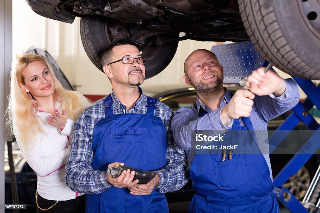 Service crew and driver near car Cheerful driver satisfied with mechanics renewal result 2015 Stock Photo