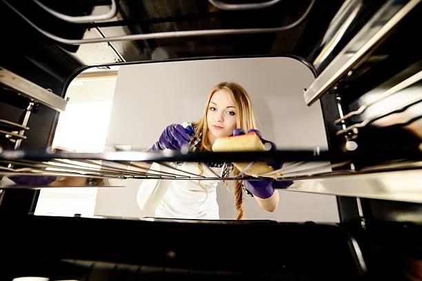 close up of woman hand  cleaning oven people, housework and housekeeping concept - close up of woman hand in protective glove with rag cleaning oven at home kitchen. View from the interior of the oven cleaning stove domestic kitchen human hand stock pictures, royalty-free photos & images