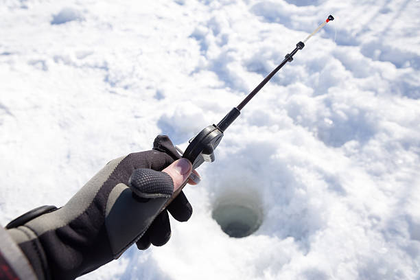 istock hand holding fishing rod lowered into hole 469787888