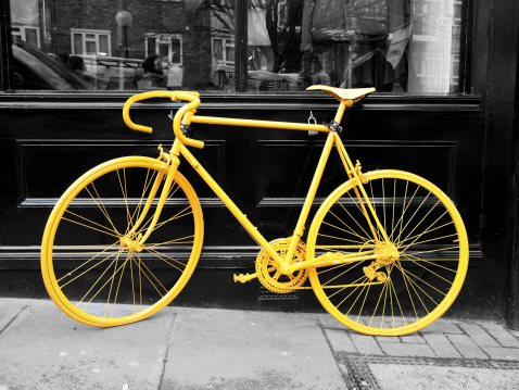 b&w photo of old yellow bike on the window of the coffe shop
