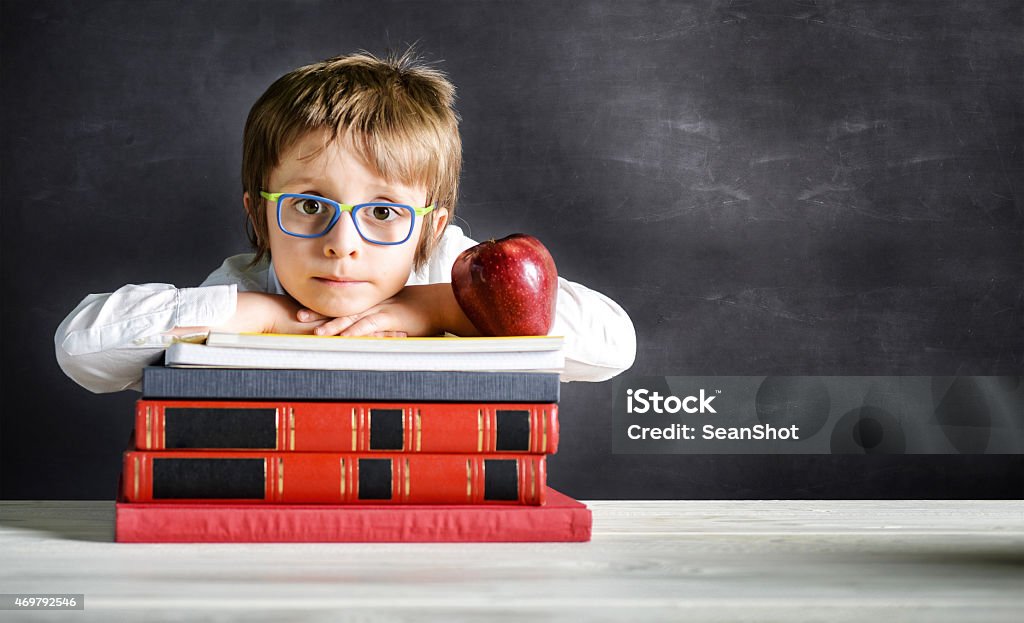 Child Leaning on Books and Copyspace Child Leaning on Books and Copyspace. Book and an apple on foreground. In the background a blackboard 2015 Stock Photo