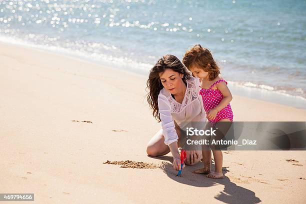 Mom And Daughter Writing In Sand Stock Photo - Download Image Now - 2015, Adult, Beach