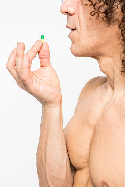 человек принимая таблеток - vitamin pill vertical high key photographic effects стоковые фото и изображения