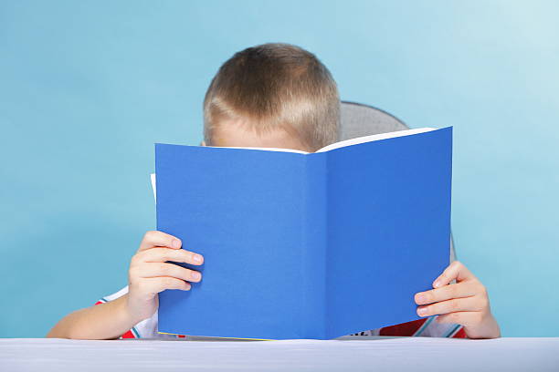 istock child boy kid reading a book on blue 469800591