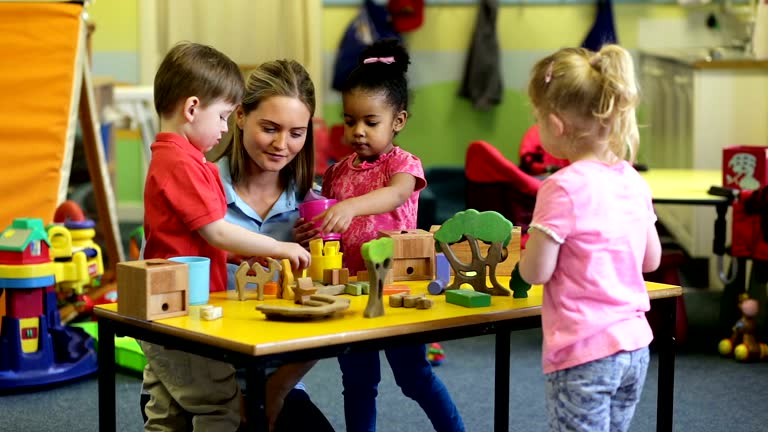 Nursery workers with children playing with toys