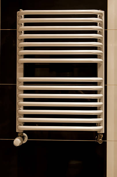 istock White bathroom heater closeup on dark brown wall 469804401