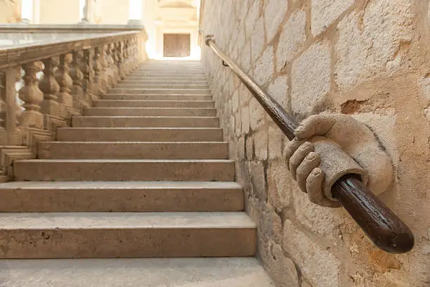 Photo of Stone hand holding stairway railing.