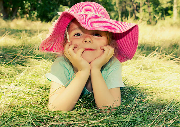 mała dziewczynka leżąc na trawie na zewnątrz.  uśmiechnięta dziewczyna twarz zbliżenie. - matthew spring zdjęcia i obrazy z banku zdjęć