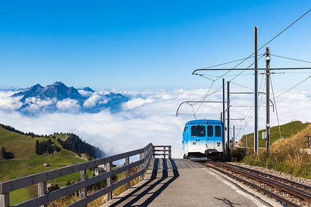 The cogwheel train for tourists running toward the top of Rigi mountain. Famous tourists place near Lucerne, Switzerland. With Pilatus above the clouds the background.