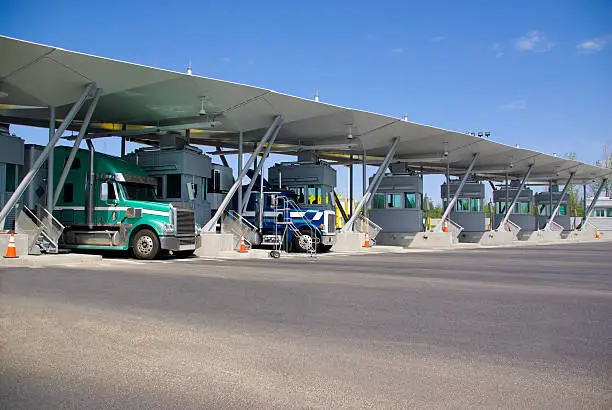 Photo of Semi trucks pay at tollbooth at Canadian border