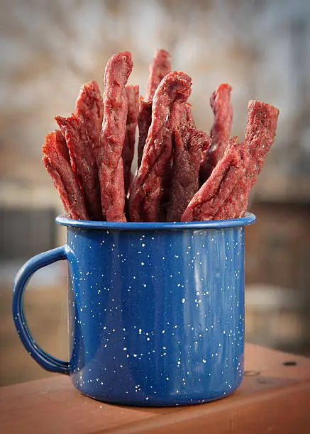 close-up mug of homemade jerky in outdoor setting