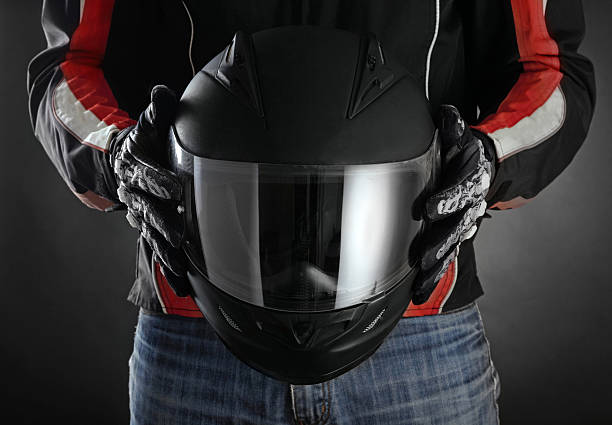 Motorcyclist with helmet in his hands. Dark background stock photo