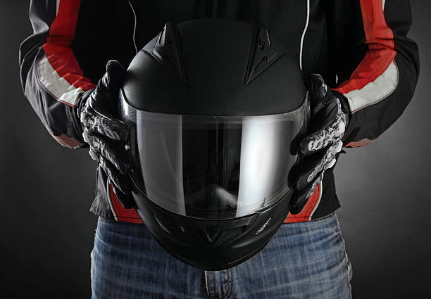 Motorcyclist with helmet in his hands. Dark background Motorcyclist with helmet in his hands. Dark background crash helmet stock pictures, royalty-free photos & images