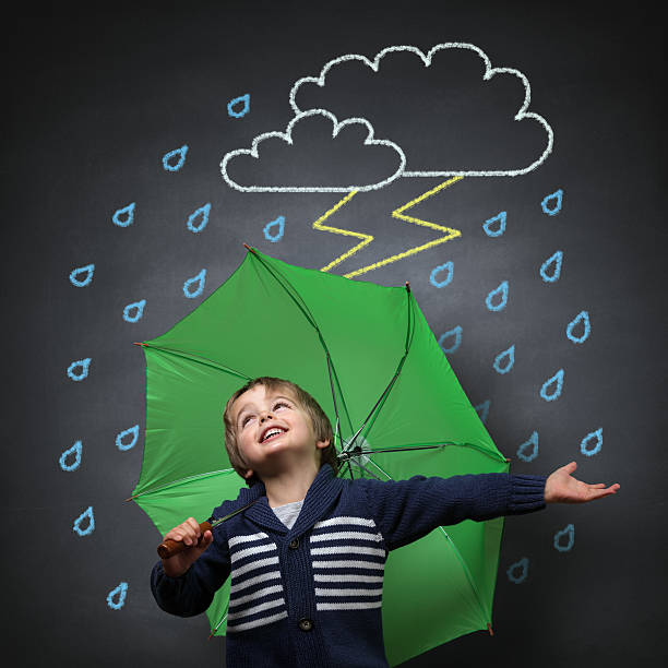 Young boy singing in the rain under a green umbrella