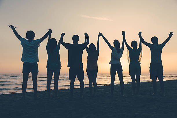 istock Individuals with raised arms on the beach at sunset 469828879