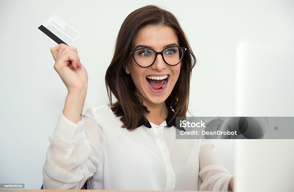 businesswoman sitting at the table Surprised businesswoman sitting at the table with bank card 2015 Stock Photo