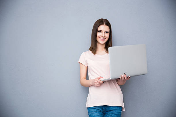 istock Smiling woman standing with laptop 469829690
