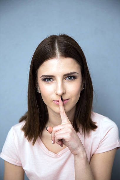 istock woman with finger over lips 469830350