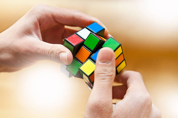 Hands playing a cube game Kranj, Slovenia - April 11, 2015: Hands playing a Rubik's Cube game.Rubik's Cube is a 3D mechanical puzzle invented in 1974 by Hungarian sculptor and professor of architecture Ernő Rubik puzzle cube stock pictures, royalty-free photos & images